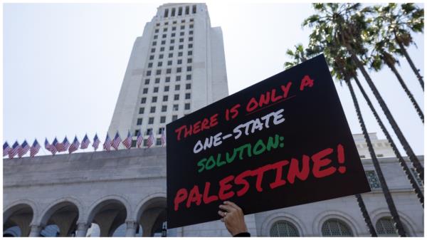 A pro-Palestinian demo<em></em>nstrator holding a placard as pro-Palestinian demo<em></em>nstrators gather in front of Los Angeles City Hall to protest anti-semitic on May 11, 2024 in Los Angeles, California. (Photo by Qian Weizhong/VCG via Getty Images)